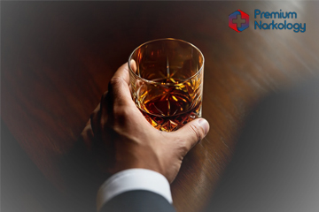 Мужчина держит стакан с алкоголем